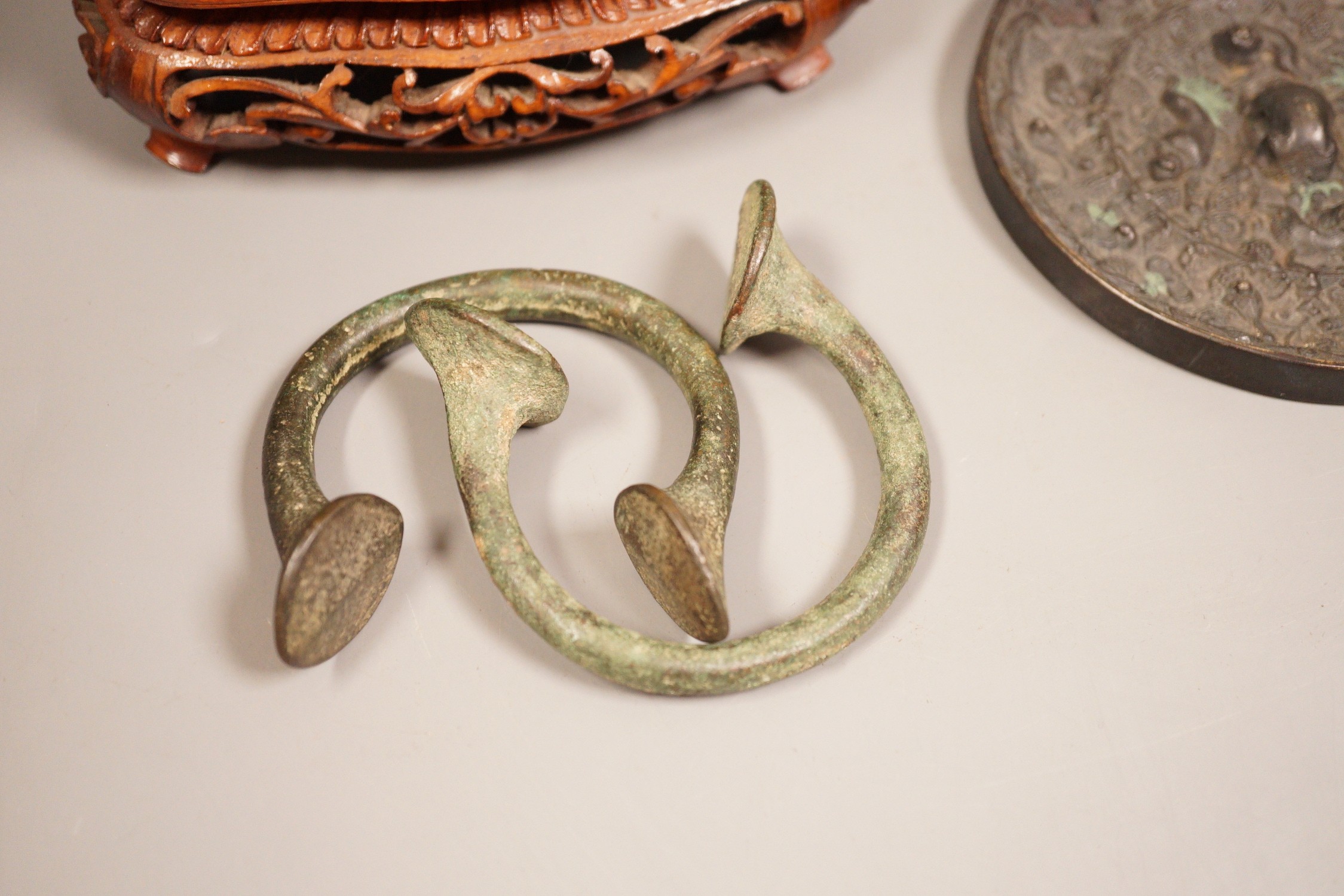 A Chinese bronze mirror, 11cm diameter, a jadeite floral carving on stand with a metal relief plaque, and a pair of bracelets
